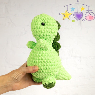 a green crocheted stuffed animal sitting on a table