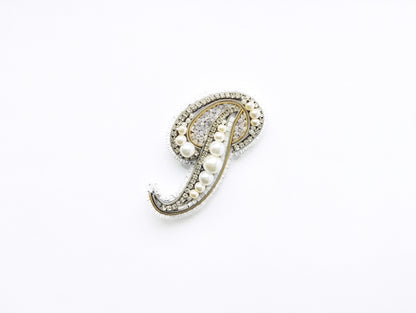 A decorative brooch with a pendant made of pearls and diamonds.