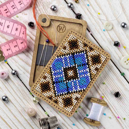 a cross stitch ornament next to a sewing needle