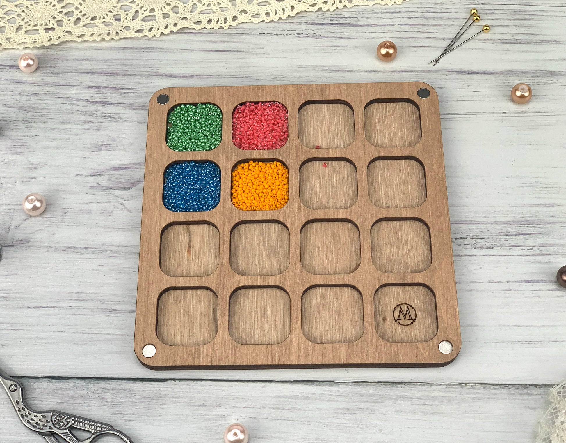 a wooden tray with beads in it on a table