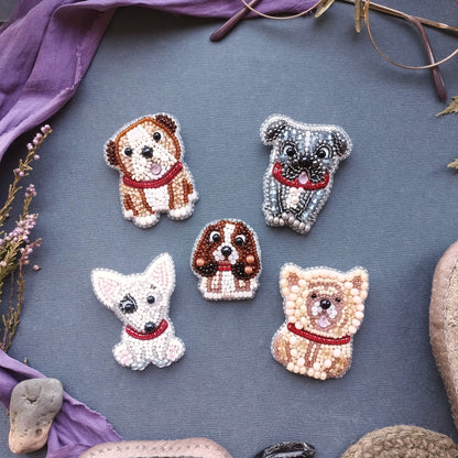 five embroidered dog brooches arranged on a gray background.