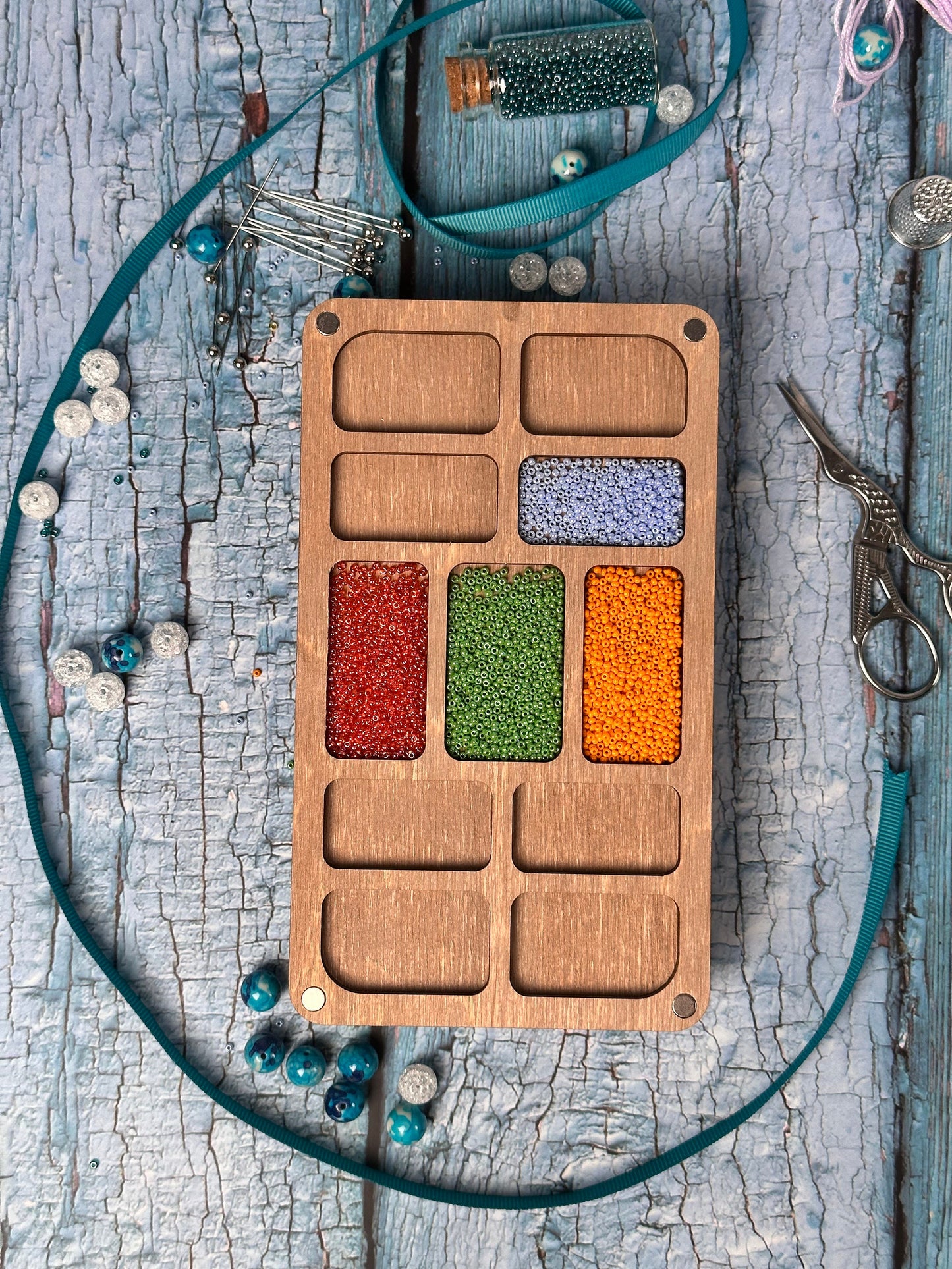 a wooden tray with beads and a pair of scissors