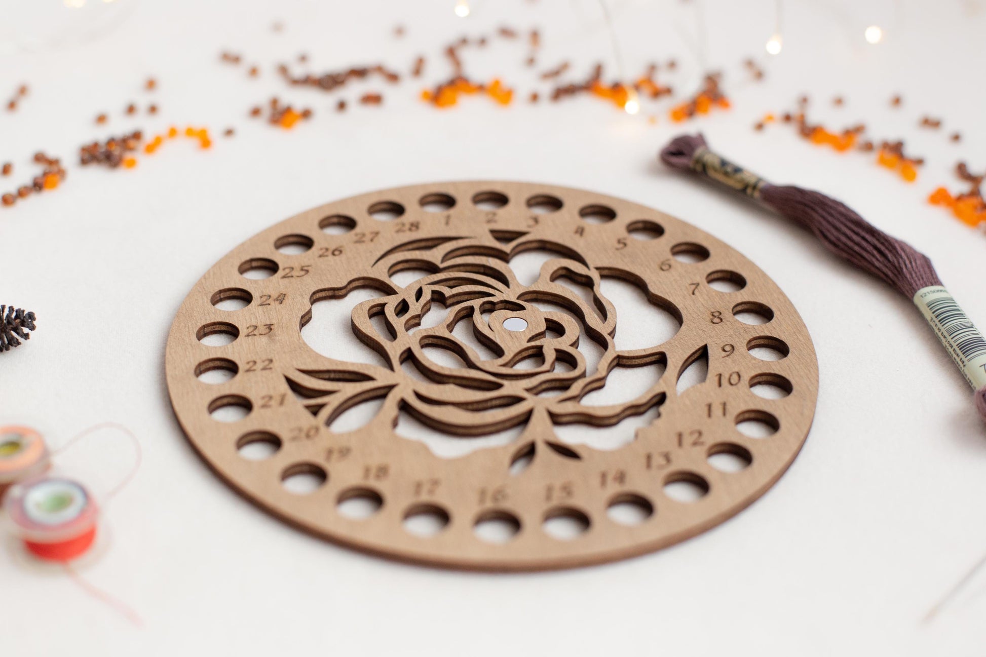 a wooden cutout of a rose surrounded by beads and thread