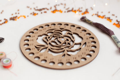 a wooden cutout of a rose surrounded by beads and thread