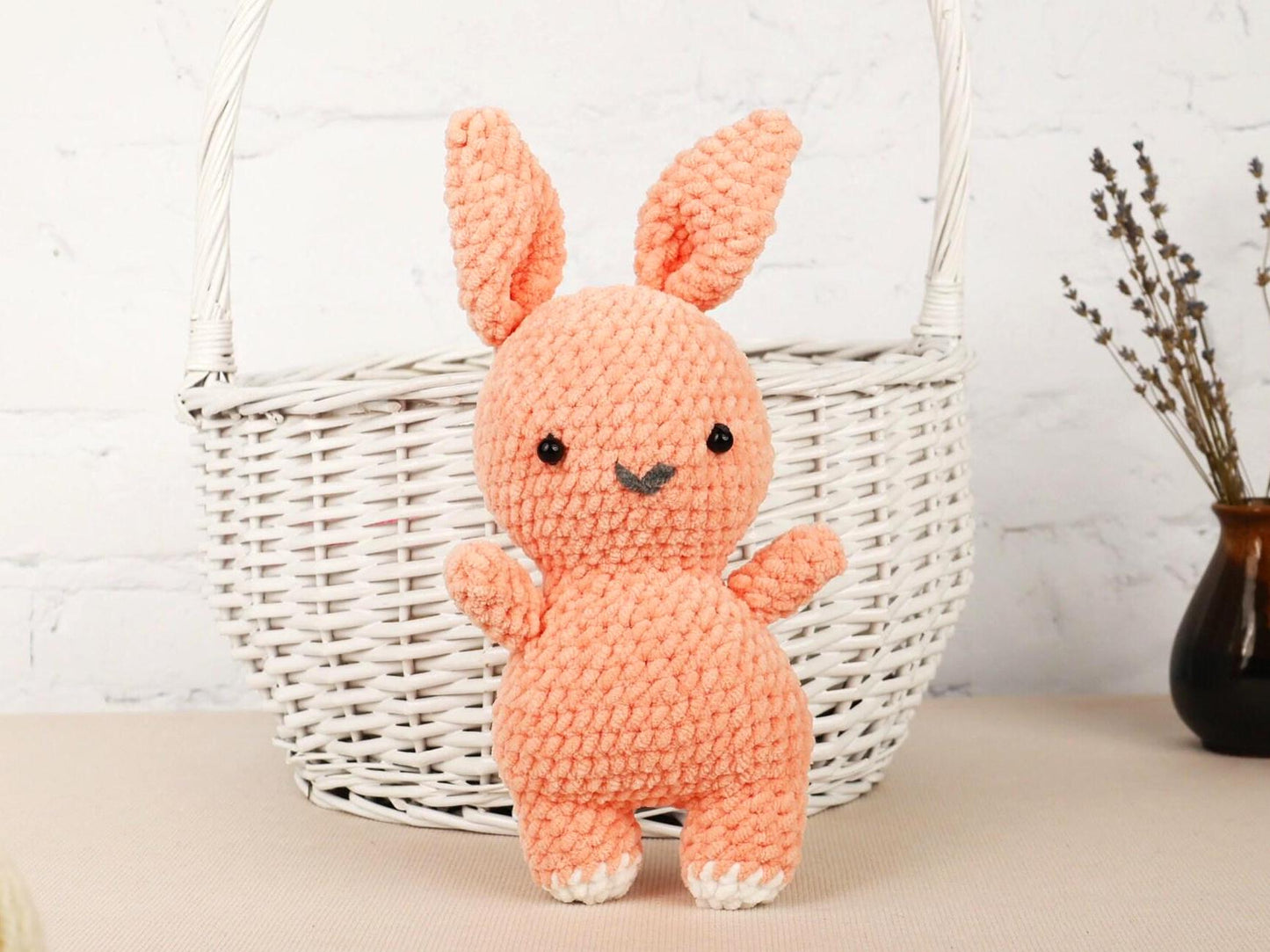 a small crocheted bunny sitting next to a basket
