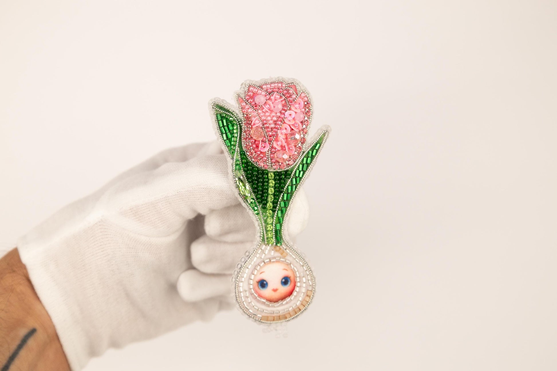 a hand in white gloves holding a pink flower