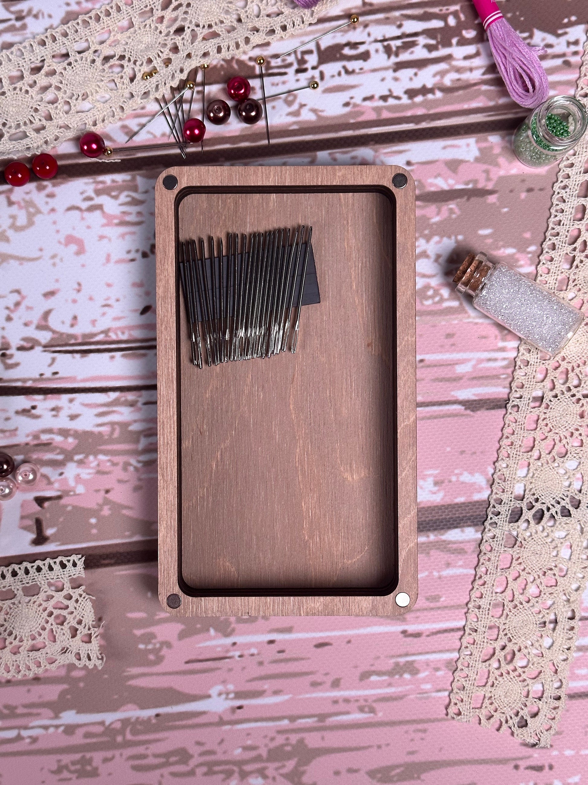 a wooden box with a bunch of black hair pins in it