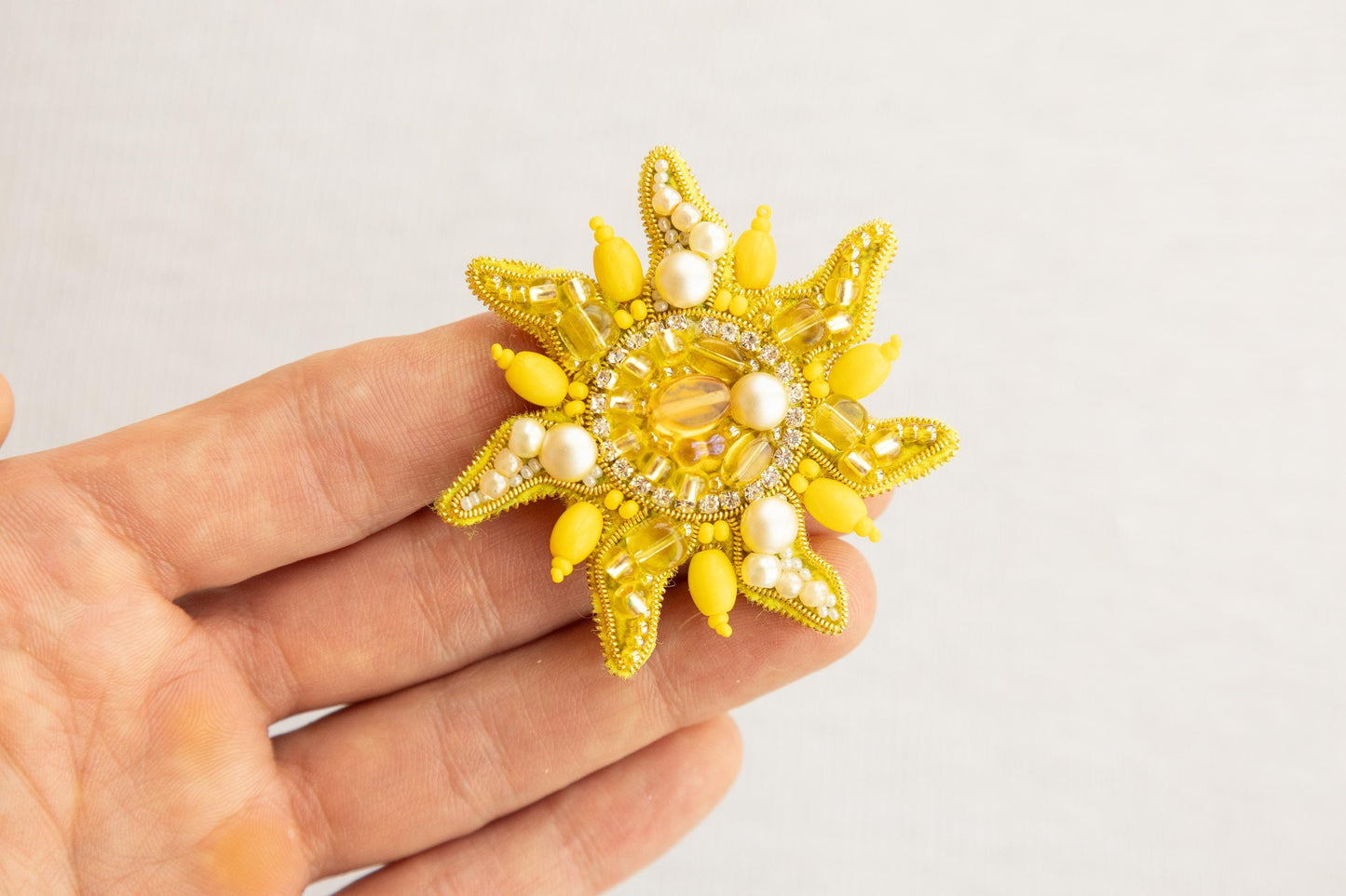 a person holding a yellow brooch in their hand