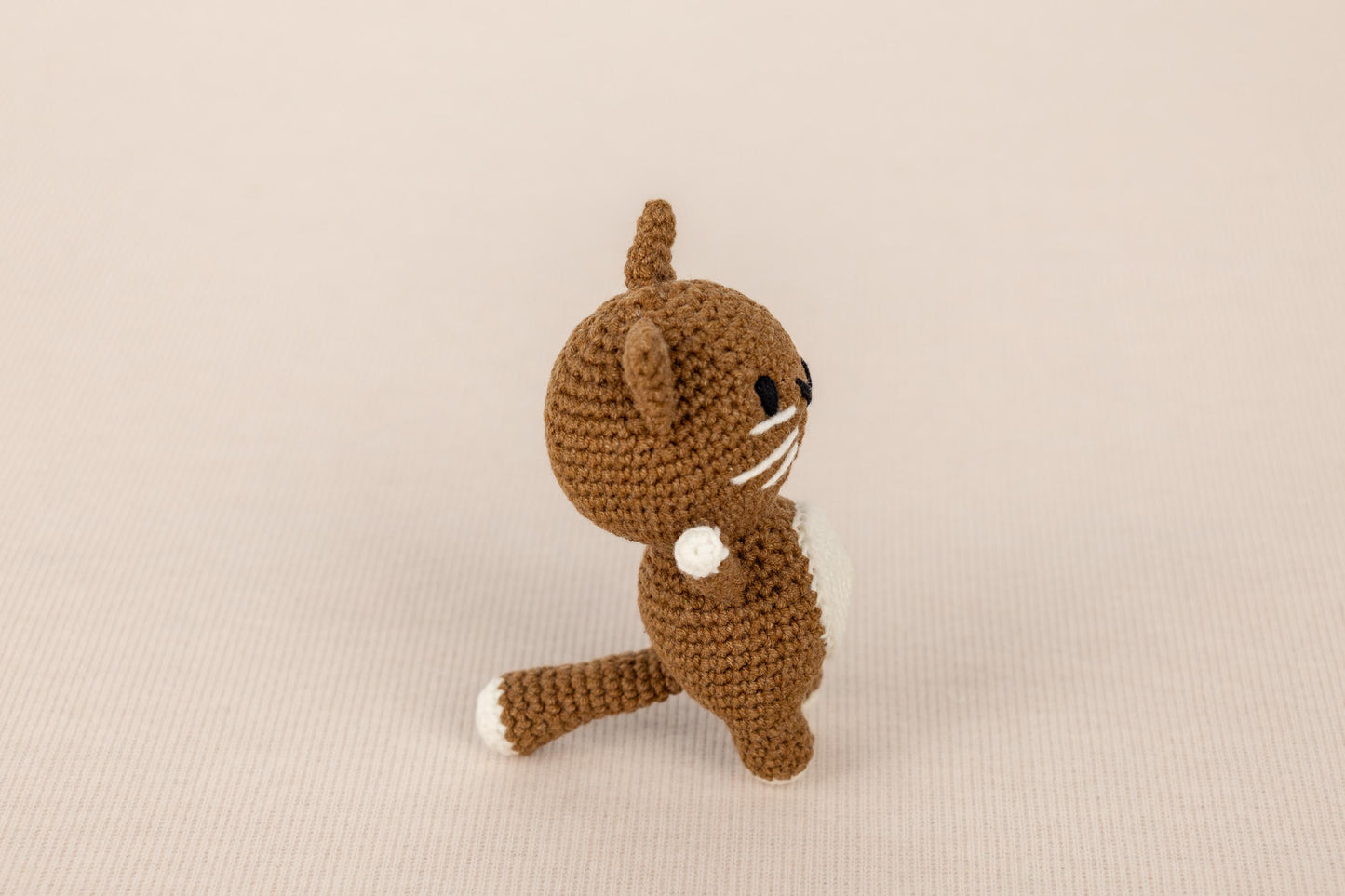 a small crocheted cat sitting on its hind legs