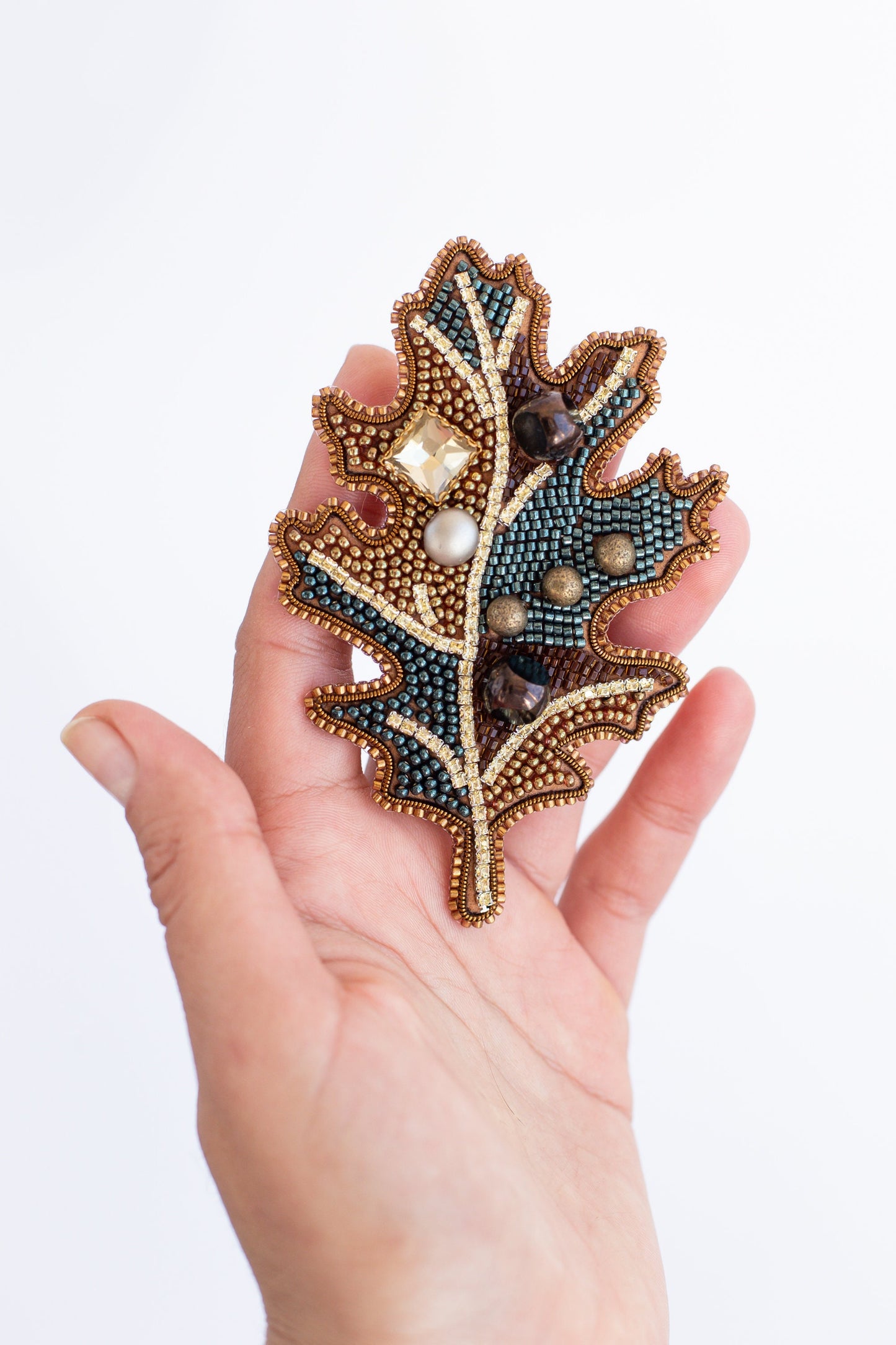 a woman&#39;s hand holding a beaded brooch