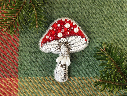 a brooch with a red and white mushroom on it