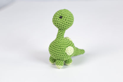 a crocheted green toy dinosaur on a white background
