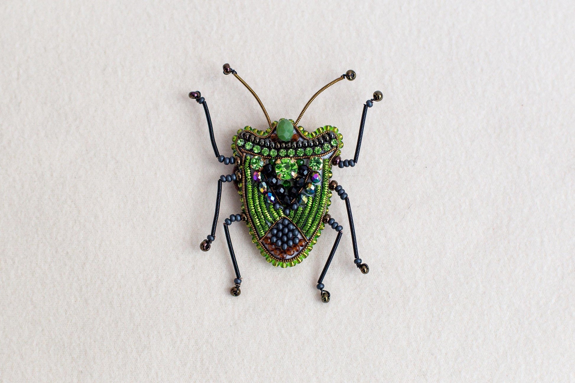 a beaded insect sitting on top of a white surface