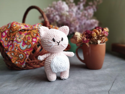 a small crocheted cat next to a basket of flowers
