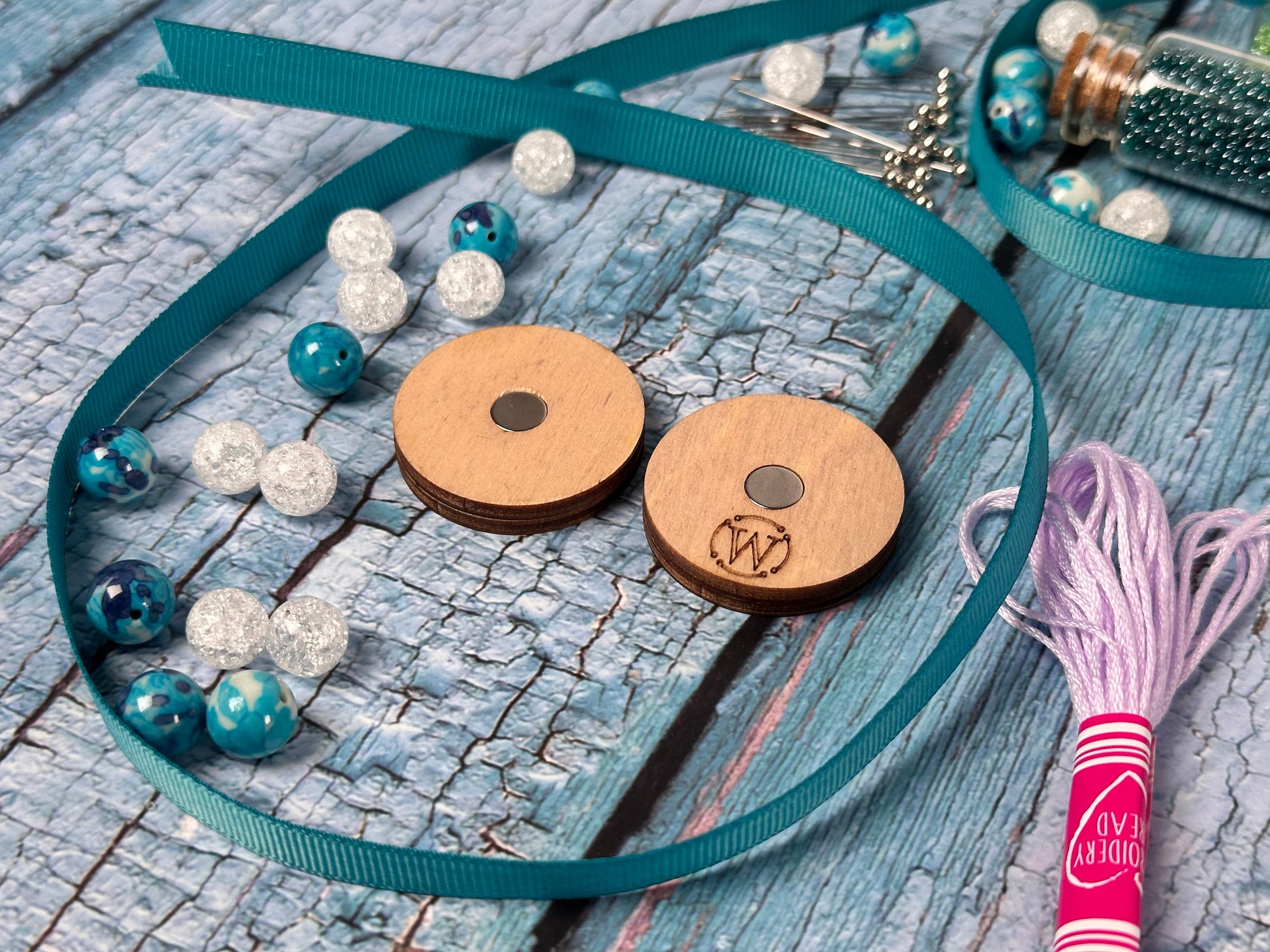 a couple of wooden buttons sitting on top of a blue ribbon