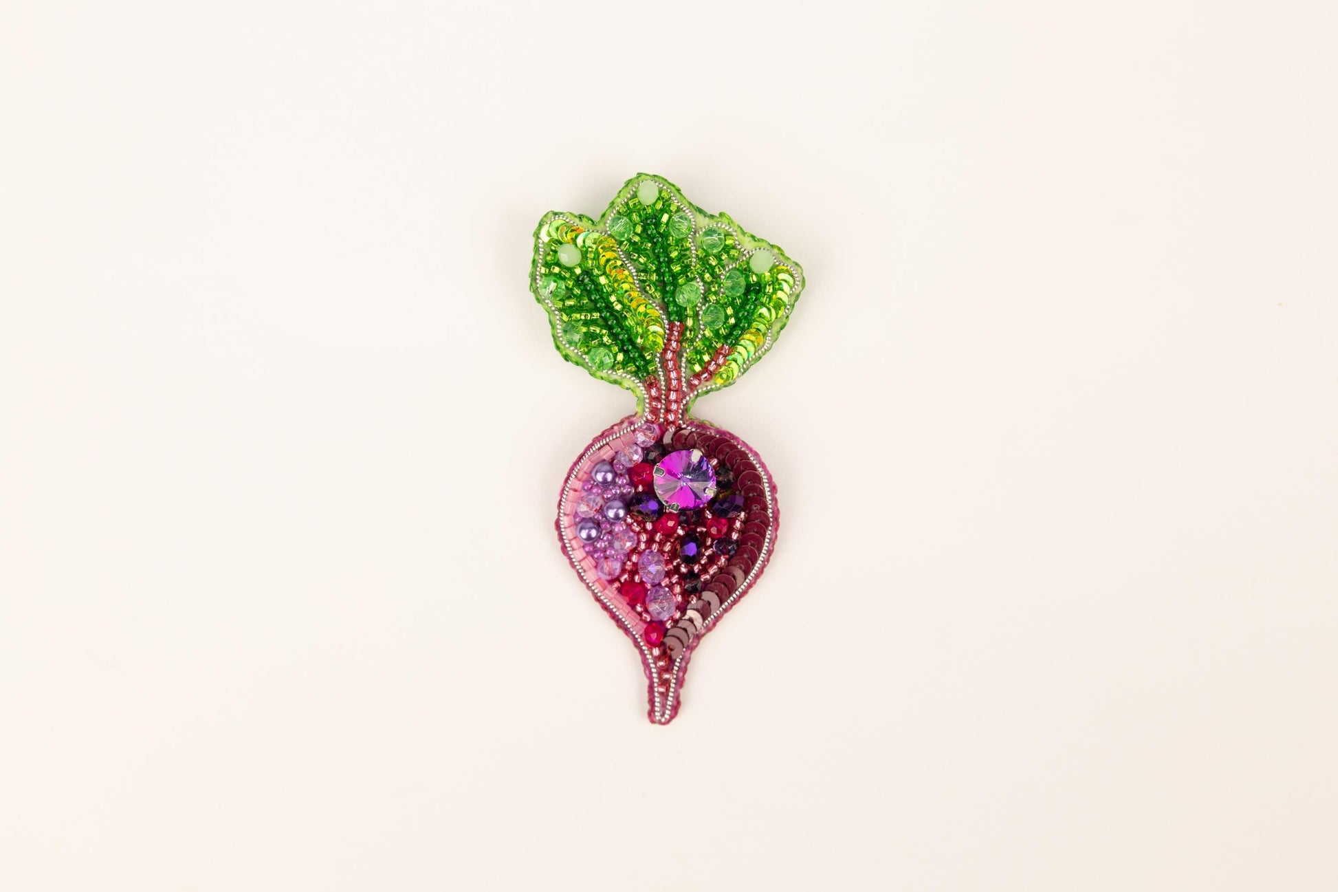 a glass brooch with a green leaf on top of it