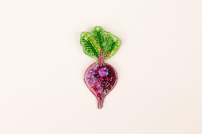 a glass brooch with a green leaf on top of it