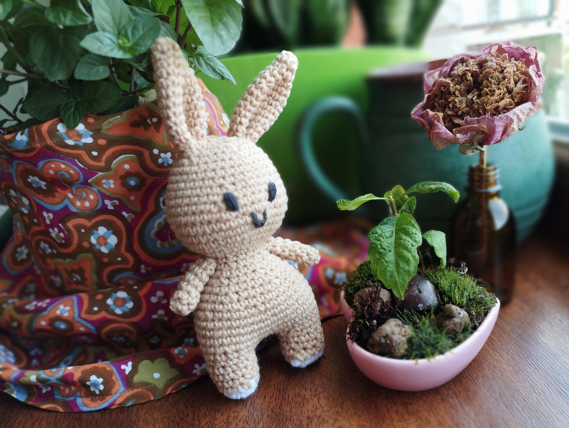 a crocheted bunny sitting next to a potted plant