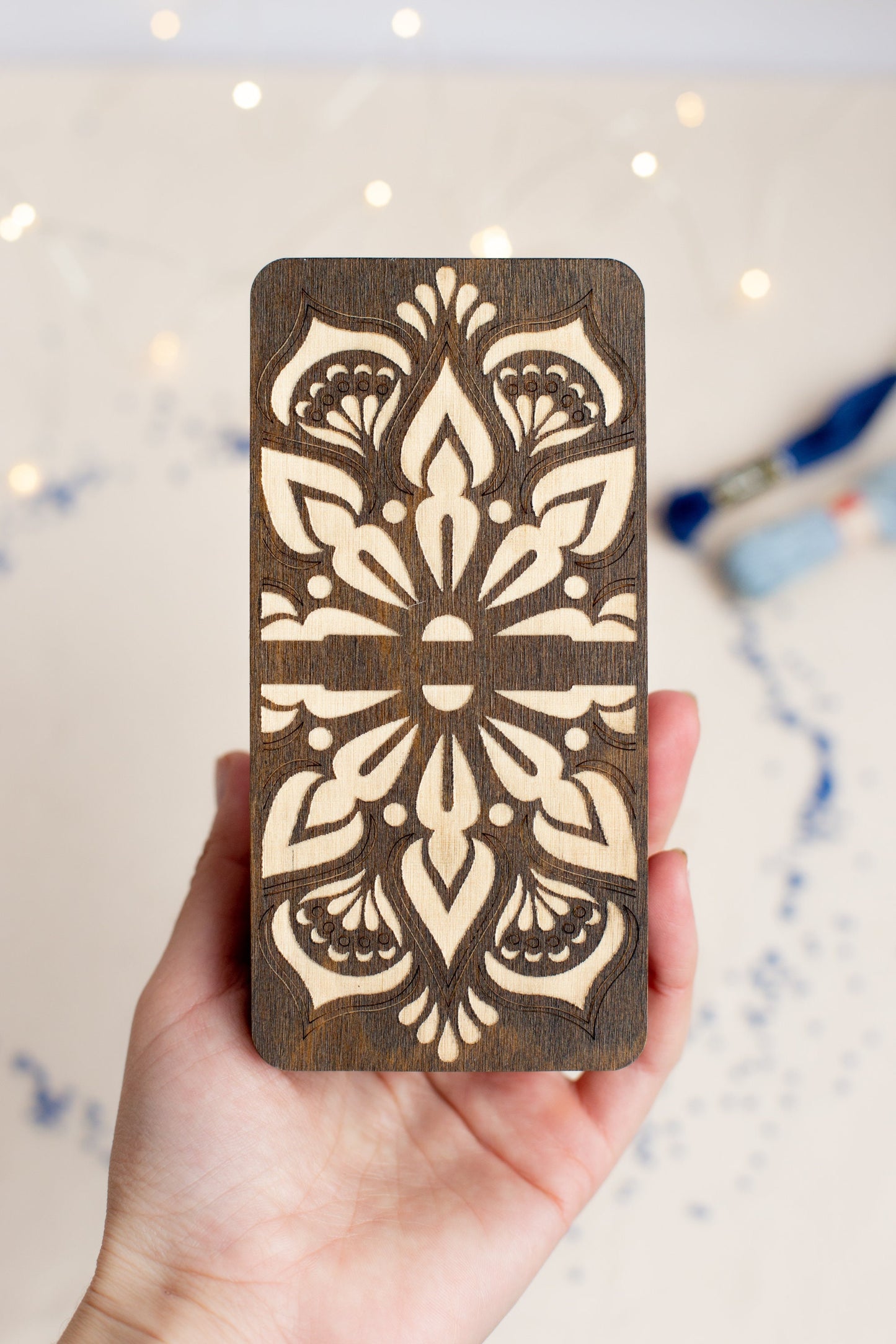 a hand holding a wooden card with a design on it