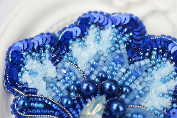 a close up of a blue and white beaded brooch