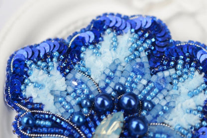 a close up of a blue and white beaded brooch