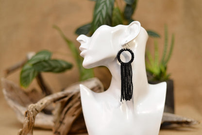 a white mannequin with a pair of earrings on it