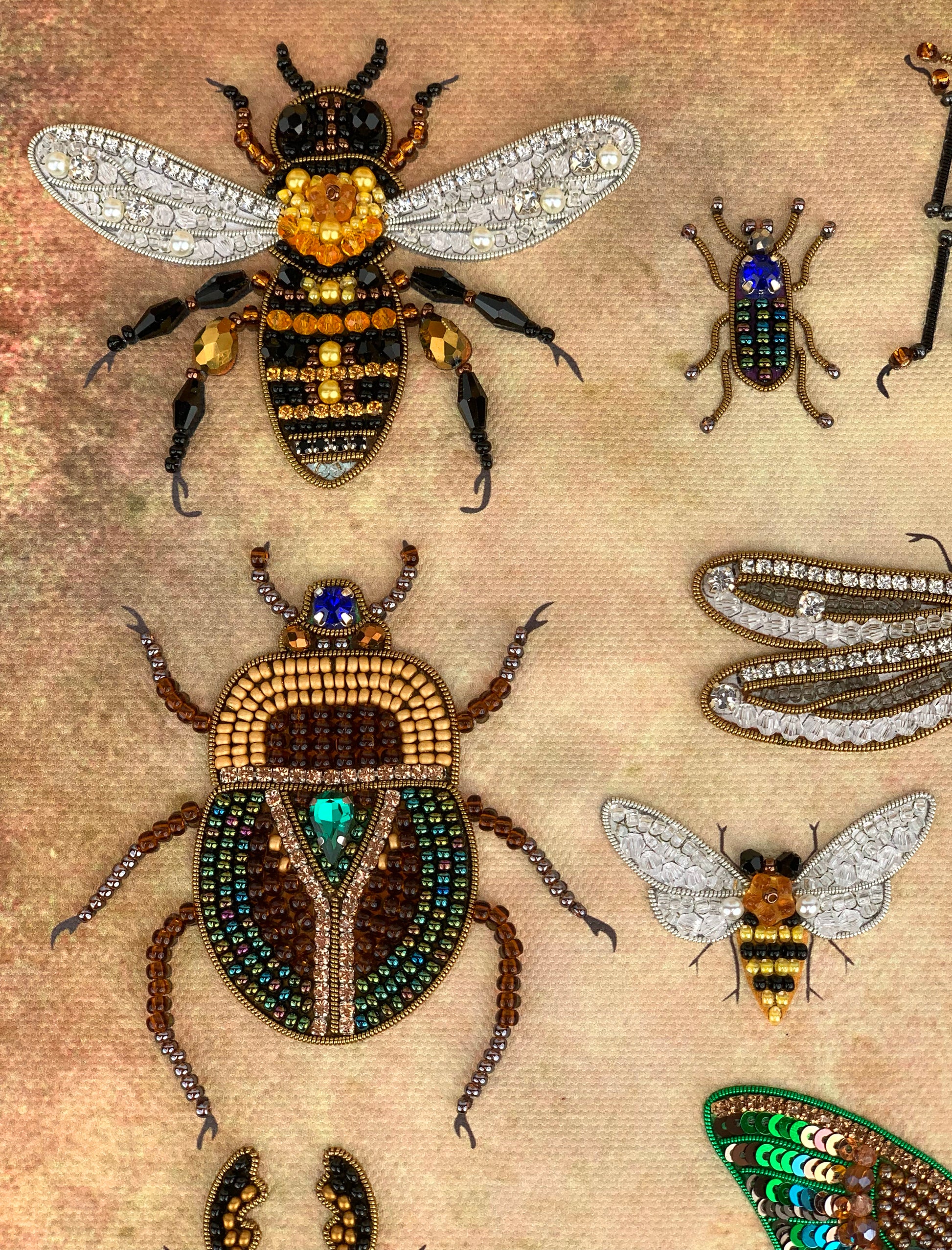 a collection of intricately designed insects, including a bee, a dragonfly, and several other types of bugs, all meticulously crafted with beads and jewels.