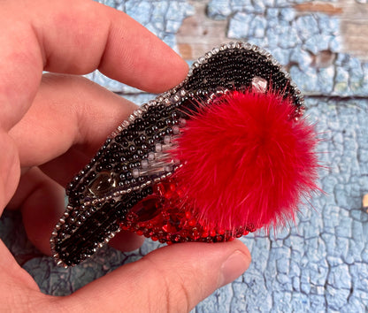a hand holding a red and black feathered object