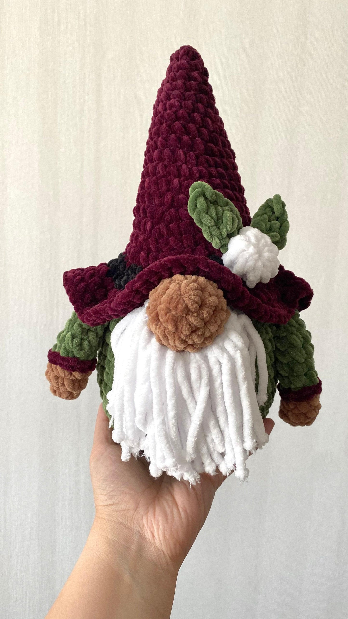 a hand holding a crocheted gnome&#39;s hat