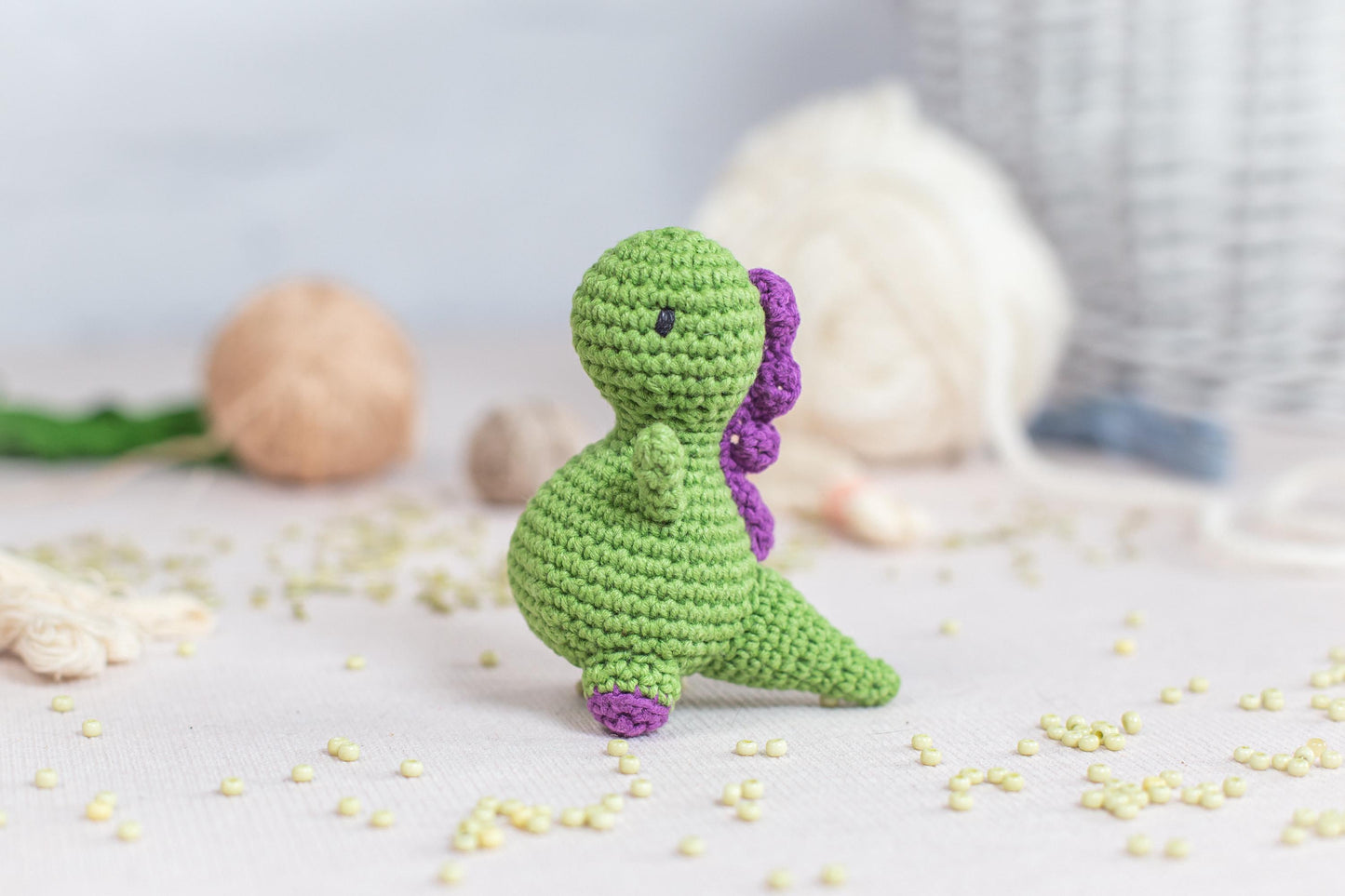 a crocheted toy of a green dinosaur sitting on a table