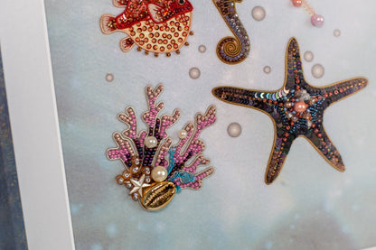 a close-up view of a collection of colorful, intricately designed sea-themed ornaments, including a starfish, a coral, and a fish, all adorned with sparkling embellishments.