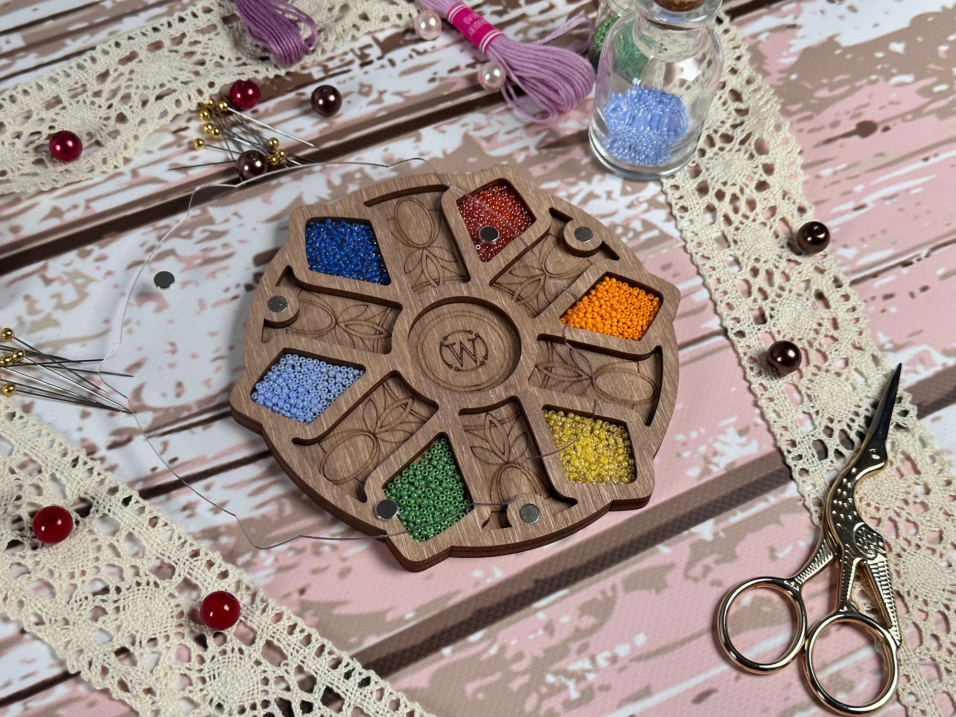 a table topped with scissors and beads next to a wooden wheel