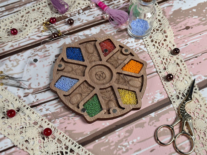 a table topped with scissors and beads next to a wooden wheel