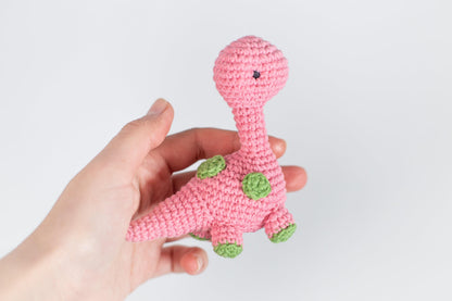a hand holding a pink crocheted toy that looks like a giraffe