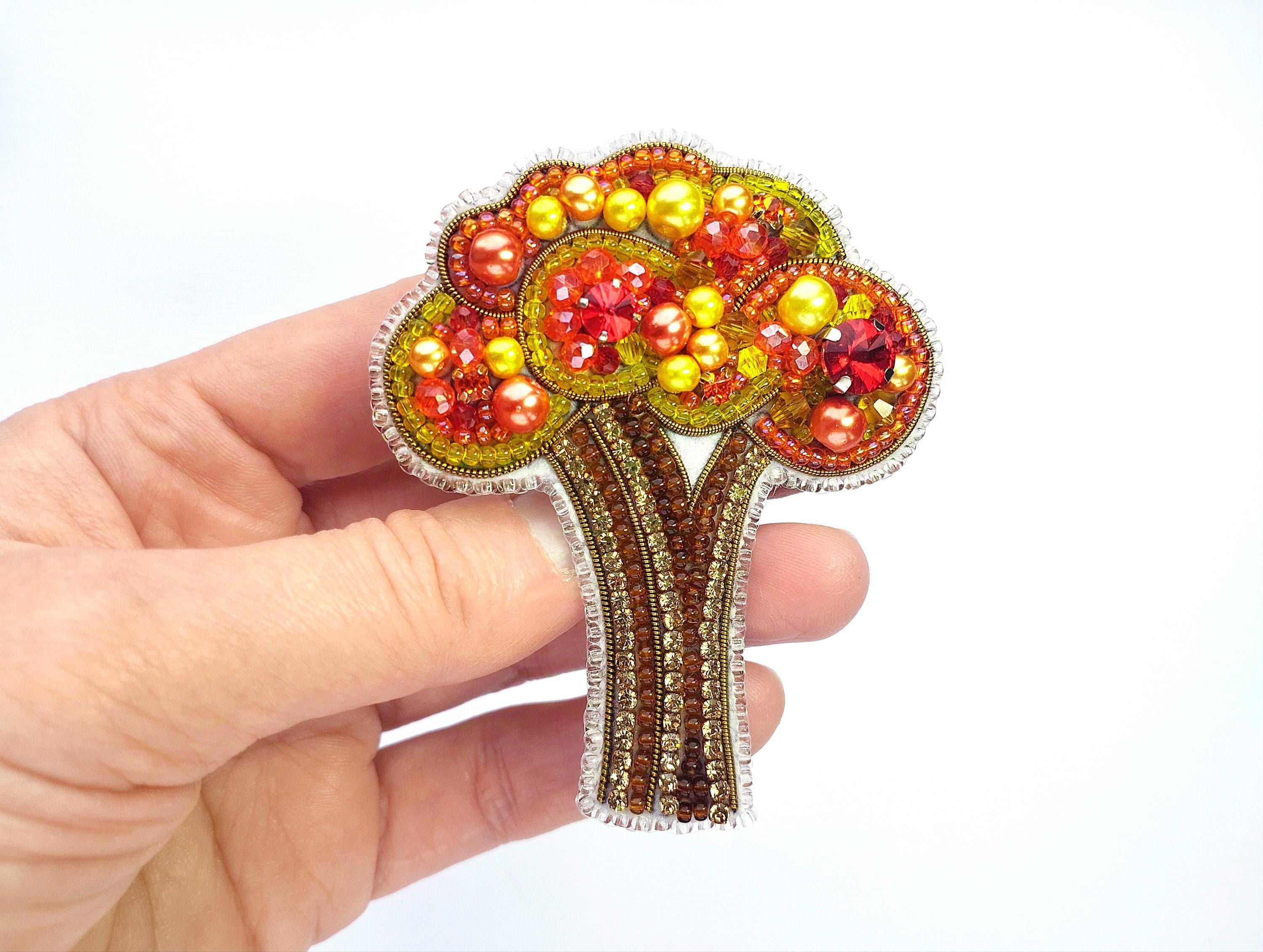 a hand holding a brooch with a tree on it