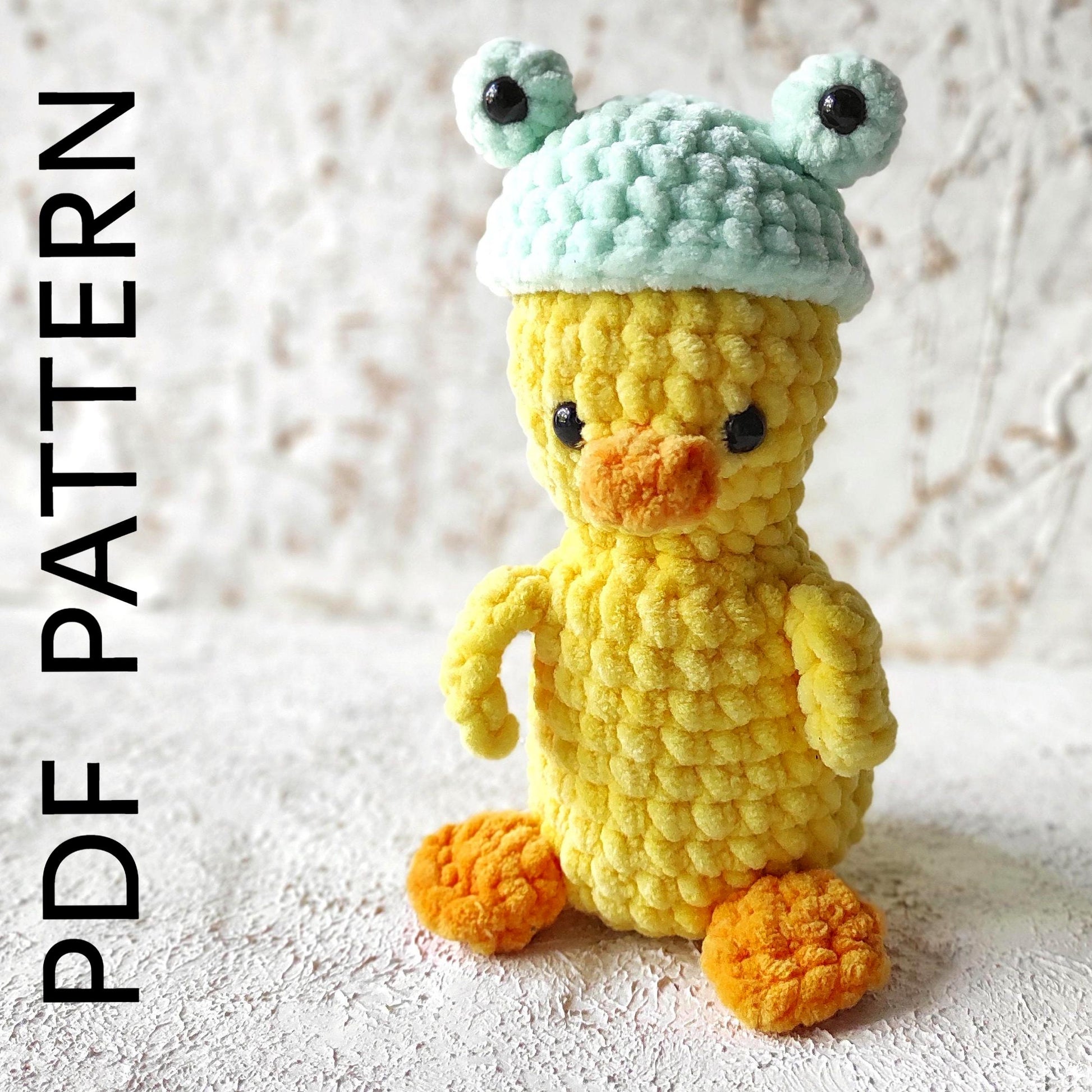 a crocheted yellow duck with a green hat