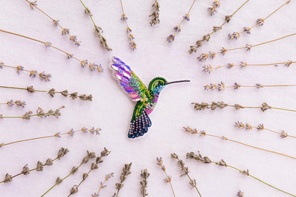a colorful hummingbird sitting on top of a field of flowers