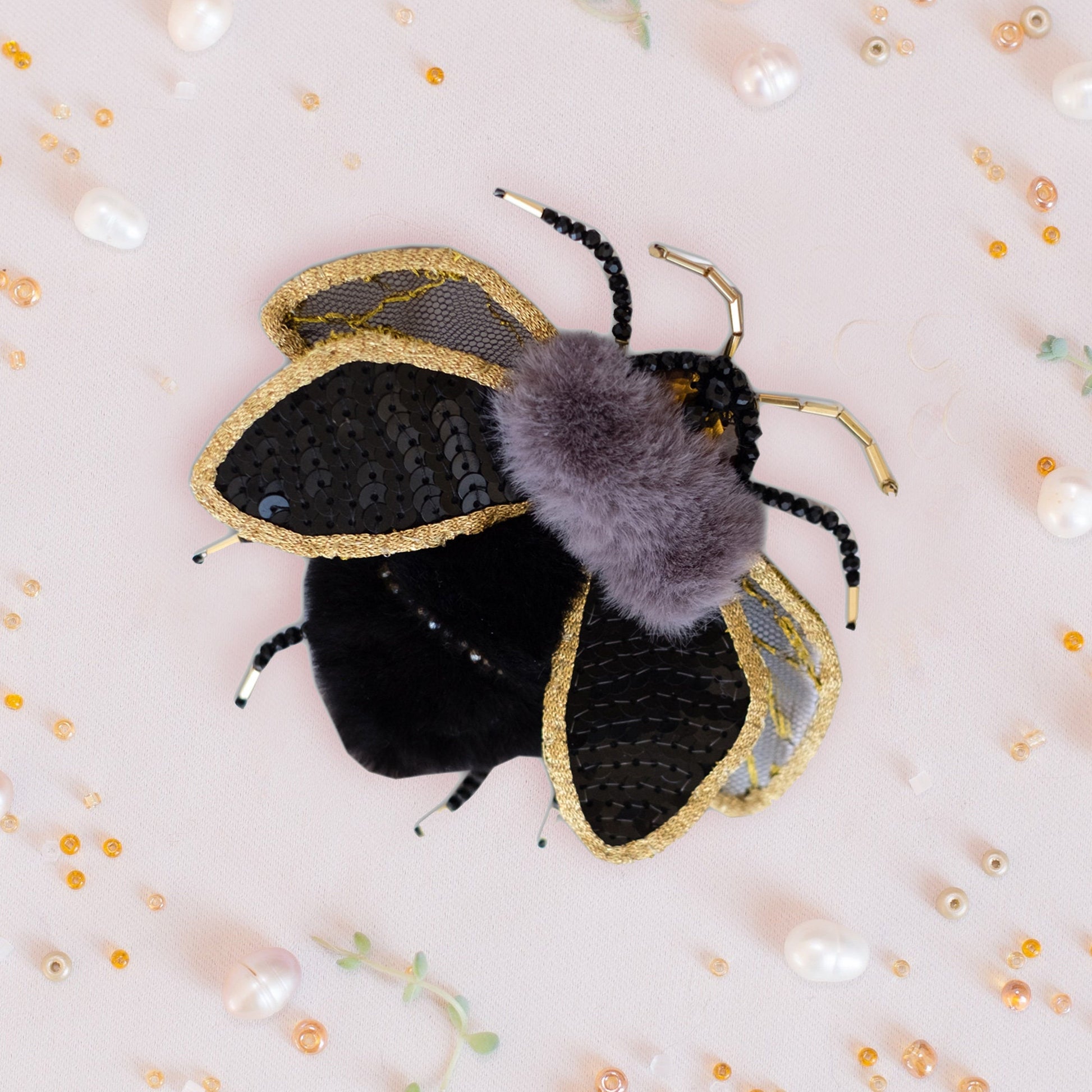 a black and gold bee with a purple fuzzy ball