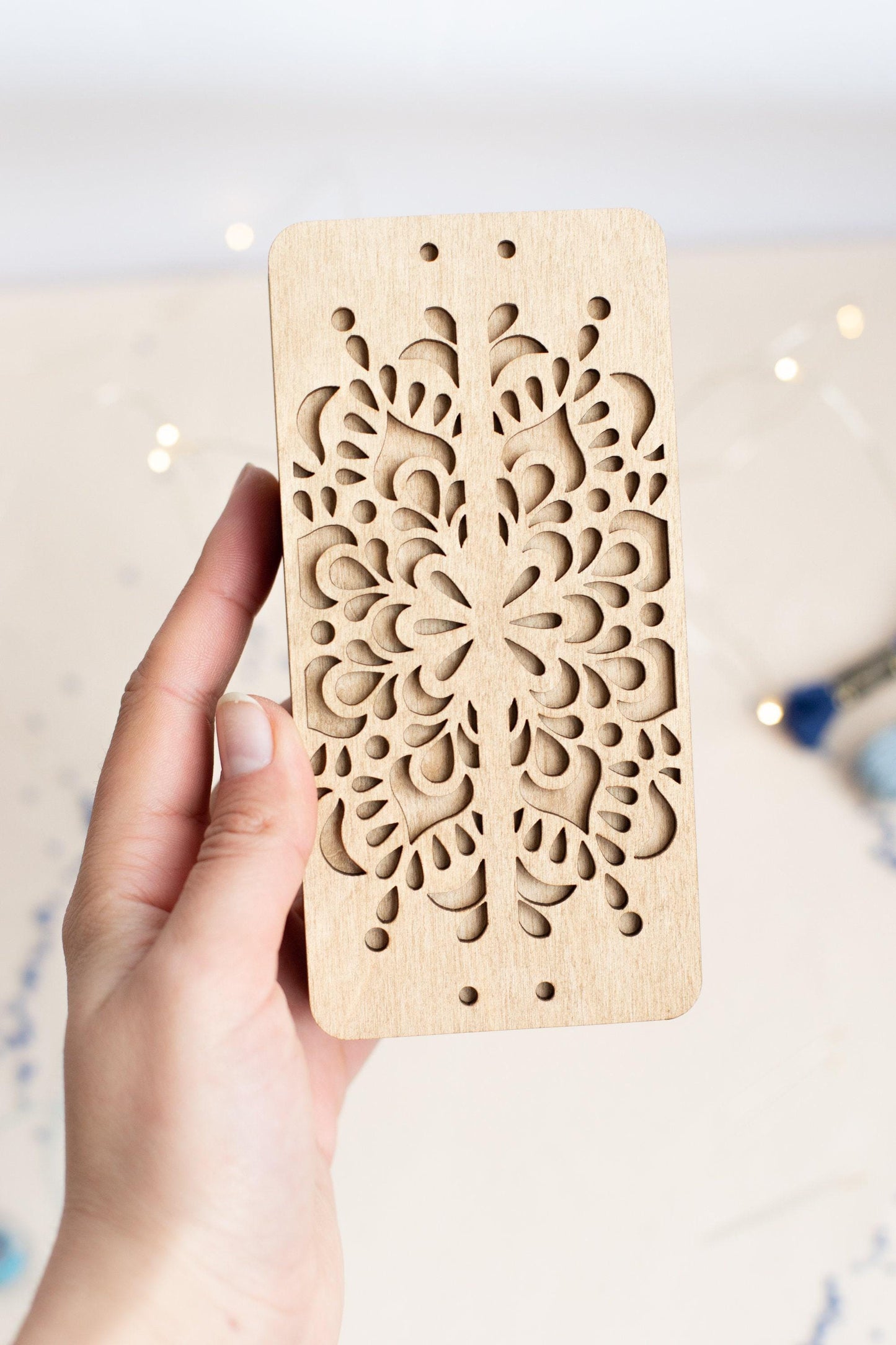 a hand holding a piece of wood with a laser cut design on it