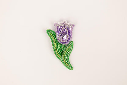 a purple and green beaded flower on a white background