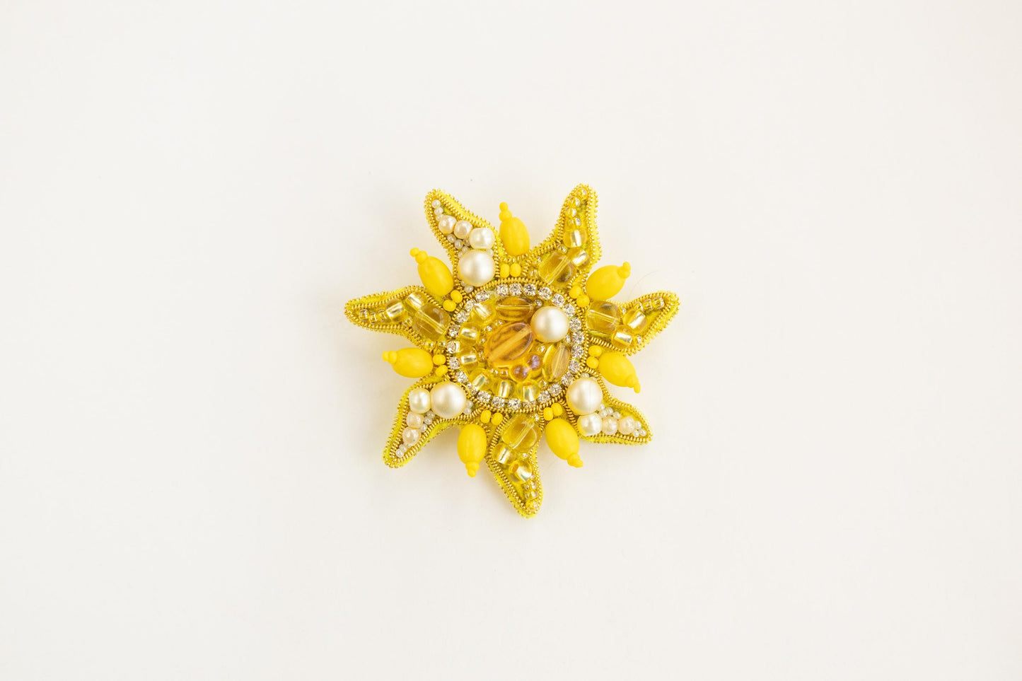 a yellow brooch with pearls on it