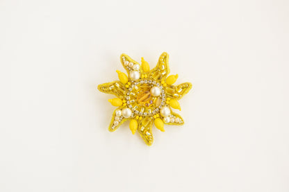 a yellow brooch with pearls on it