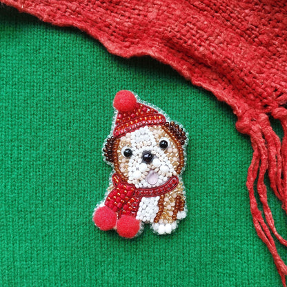A small embroidered dog wearing a red hat and scarf is displayed against a green background, with a red scarf partially visible on the right side.