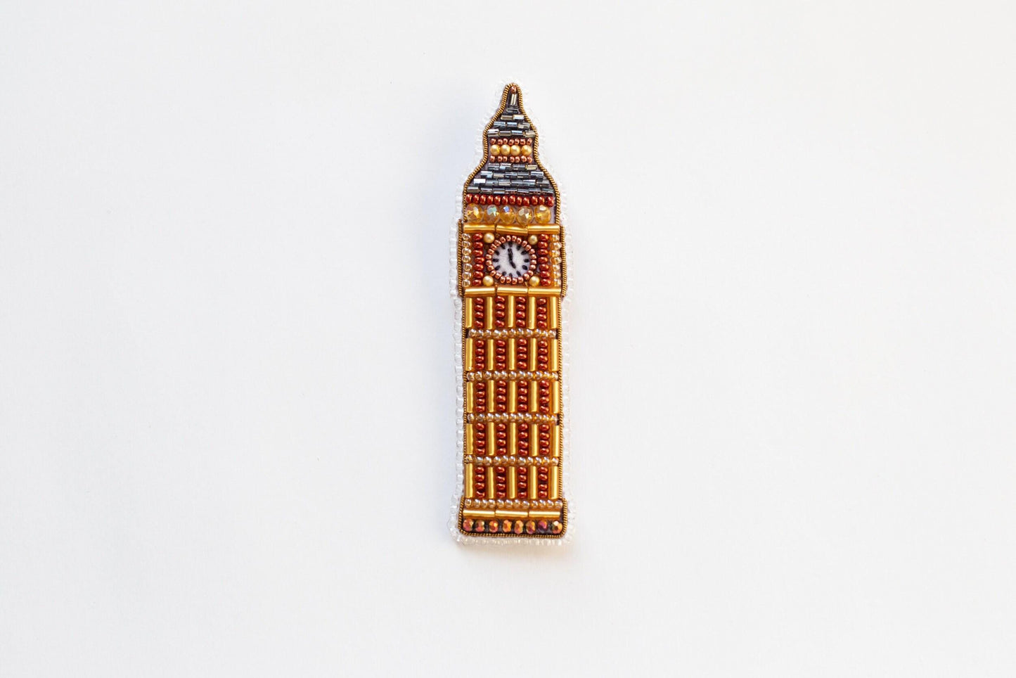 a brooch with a clock on it on a white surface