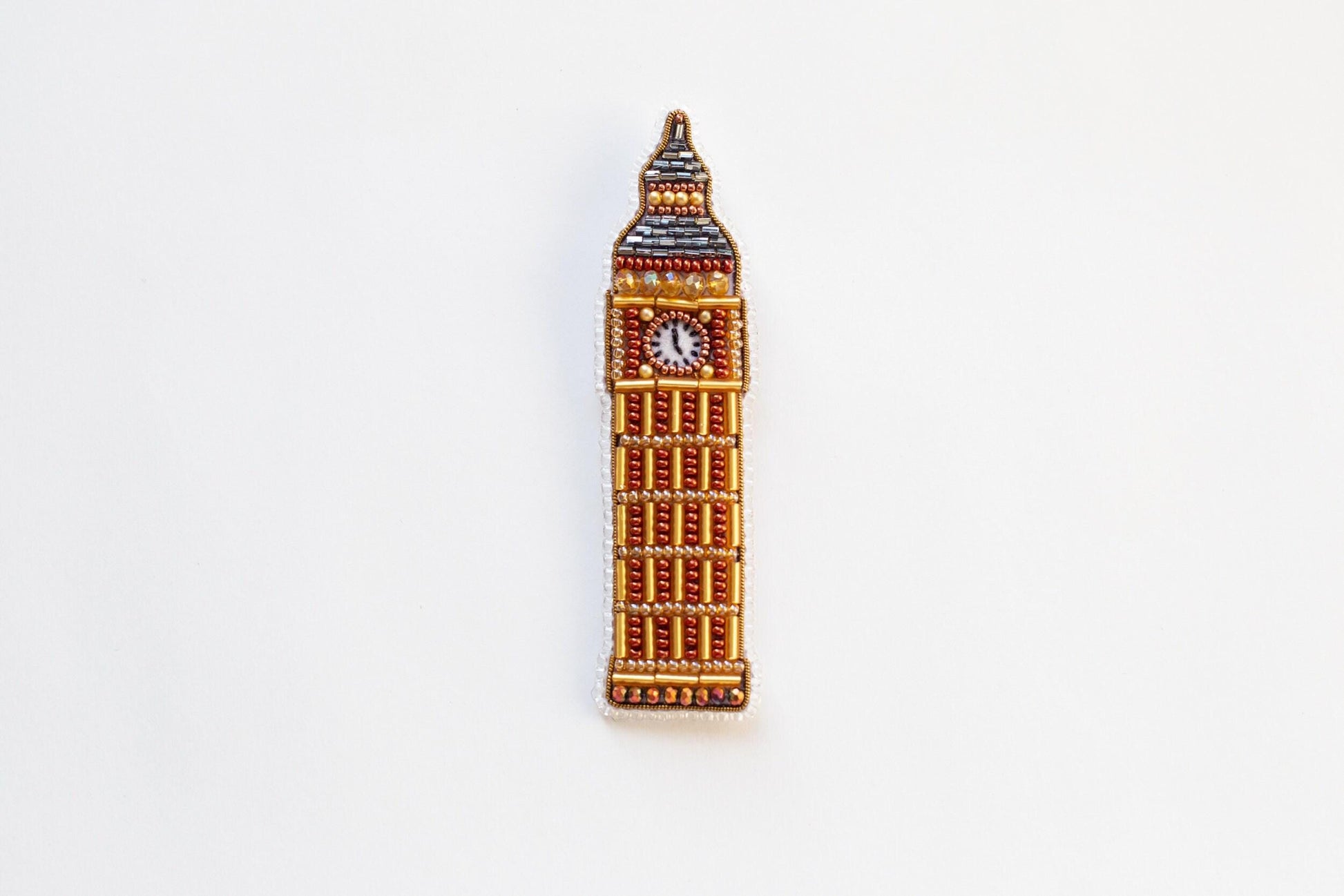 a brooch with a clock on it on a white surface