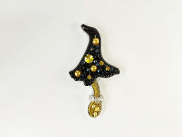 a black hat with gold beads hanging from a hook