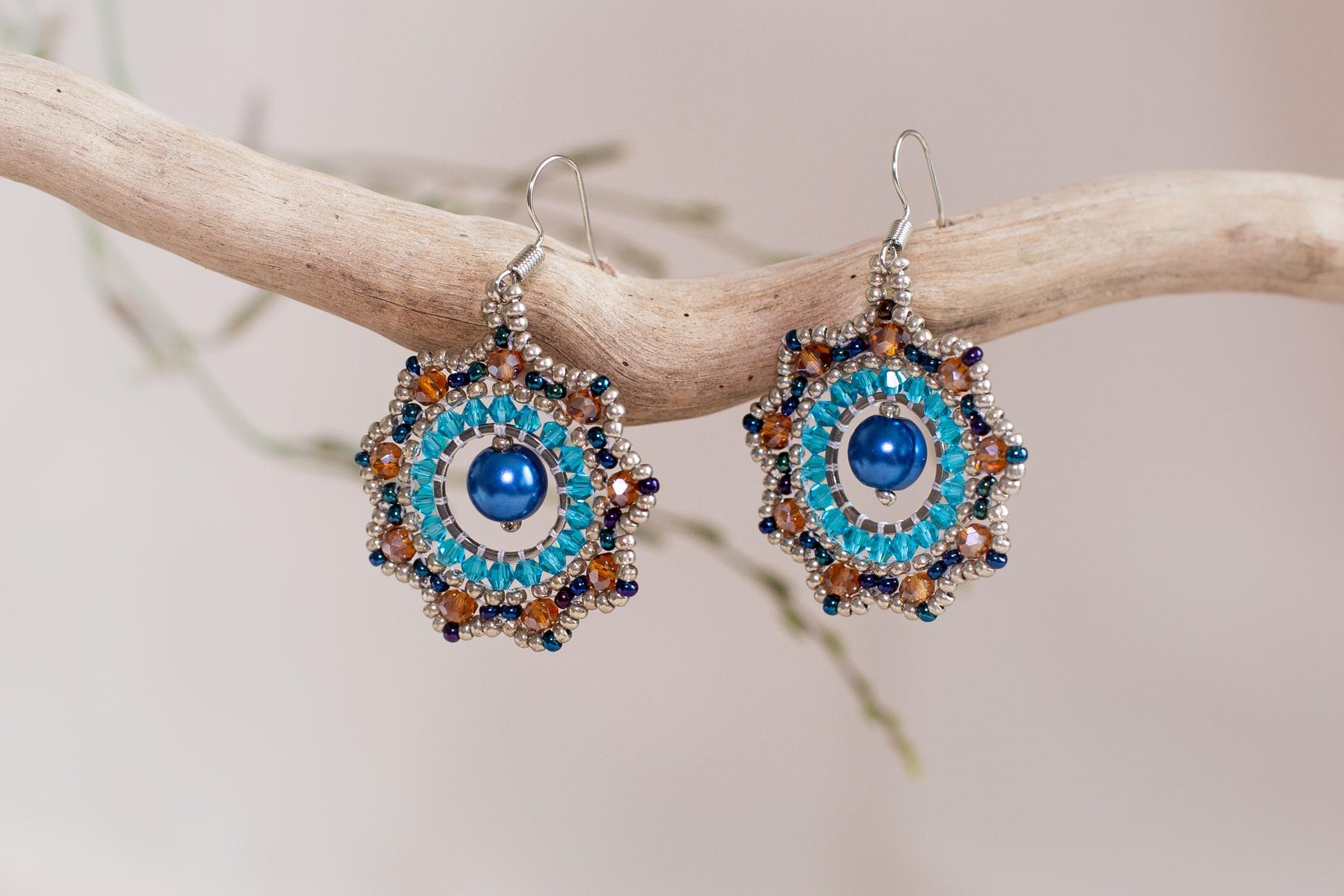 a pair of blue and orange earrings on a branch