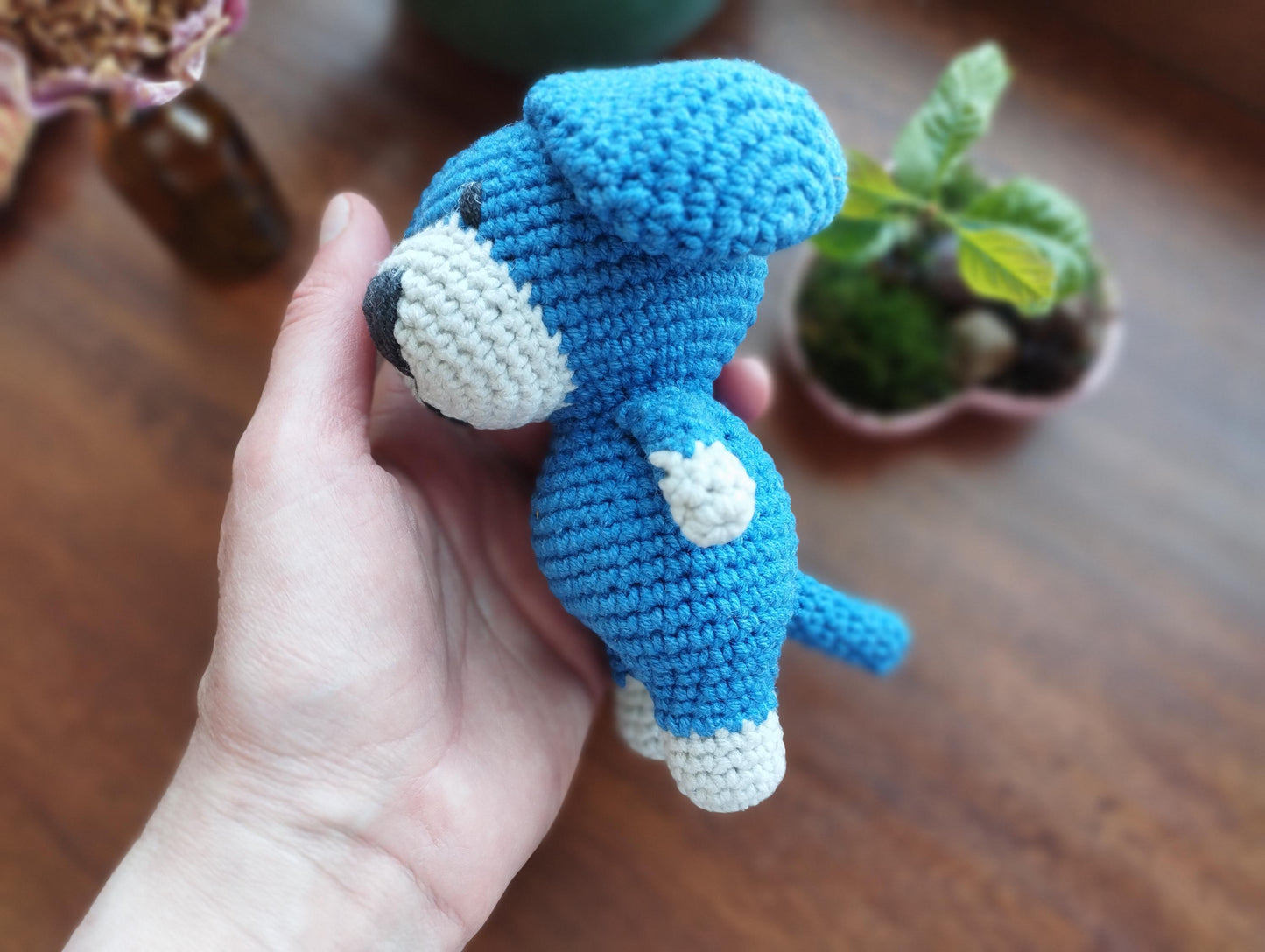 a hand holding a small crocheted stuffed animal