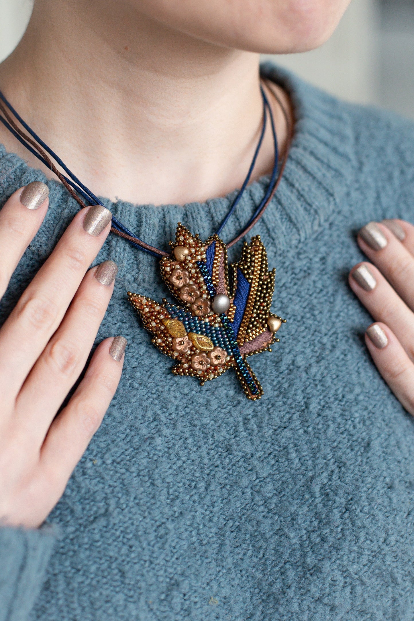 a woman wearing a blue sweater and a beaded necklace
