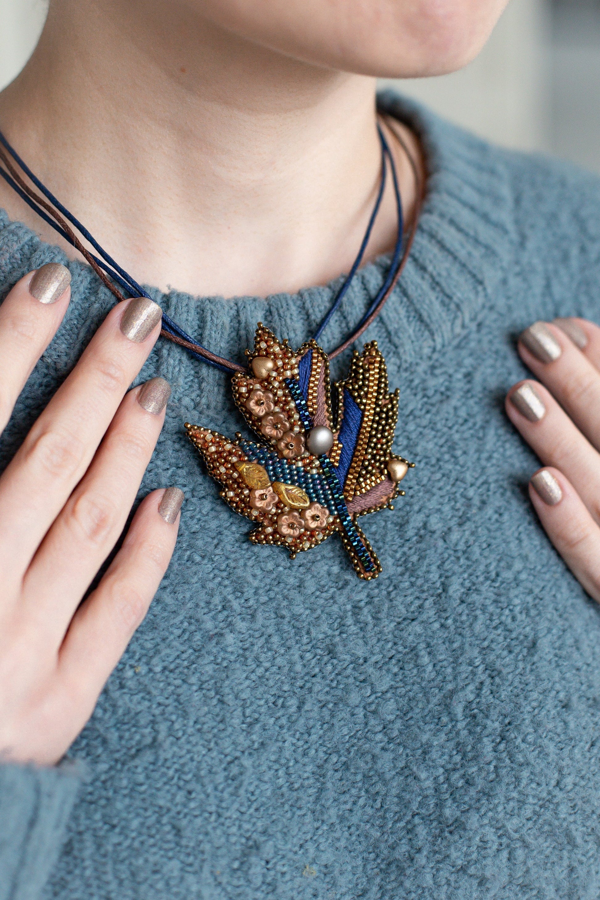 a woman wearing a blue sweater and a beaded necklace